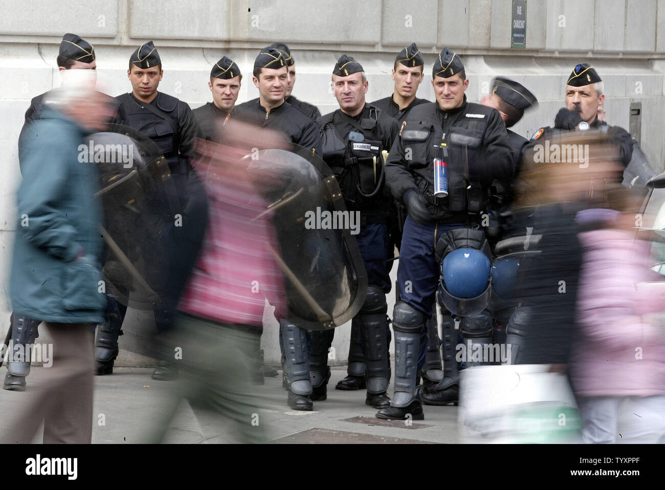 People walk past a barricade of anti-riot police blocking off a street during a protest march along one of Paris' main avenues April 11, 2006. Hundreds of students, emboldened by President Jacques Chirac's cave-in on the First Employment Contract (CPE), went ahead with a pre-planned demonstration in a bid to get rid of other government labor reforms.  (UPI Photo/Eco Clement) Stock Photo