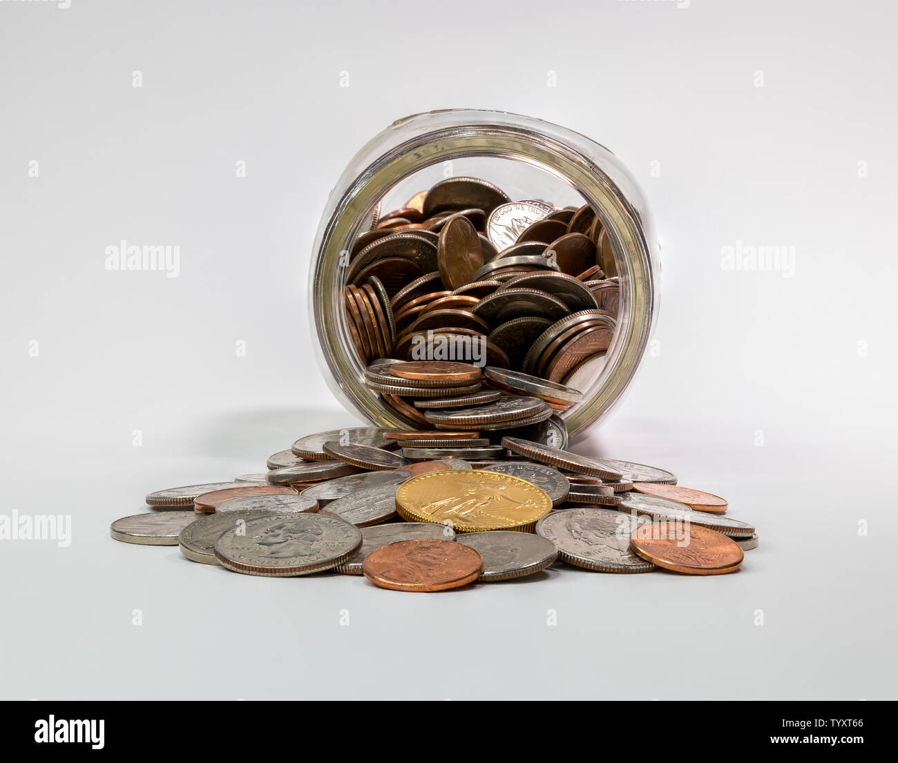 Spare change jar laying on its side with coins spilling out Stock Photo