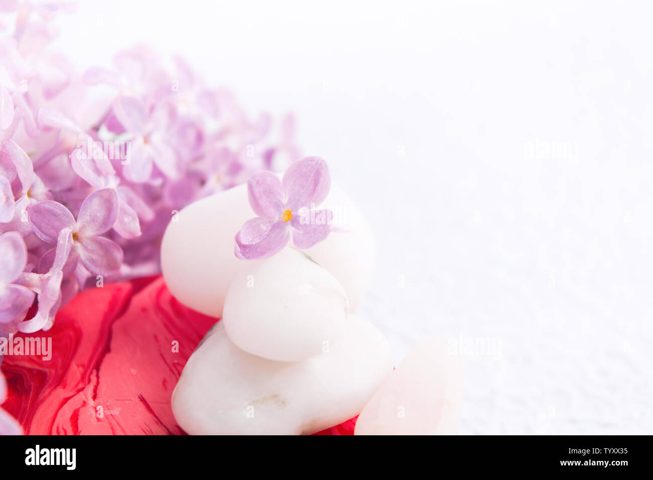 Spa and massage relaxation concept with white stones. red handmade soap and lilac flowers on white textured background with copy space. Selective focu Stock Photo