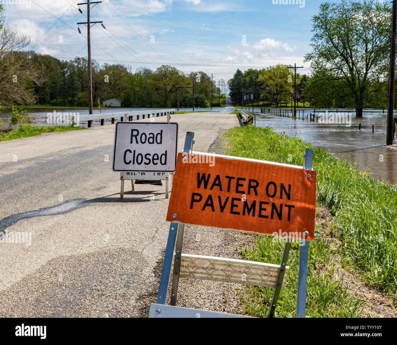 Heavy rains and storms have overflowed rivers and streams causing road closed warning signs to be installed at flooded road locations Stock Photo