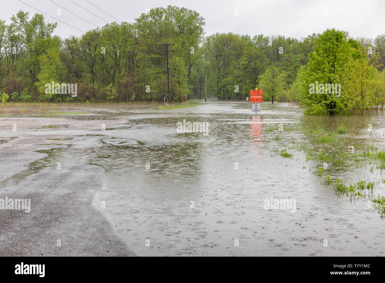 Heavy rains and storms have overflowed rivers and streams causing road closed warning signs to be installed at flooded road locations Stock Photo