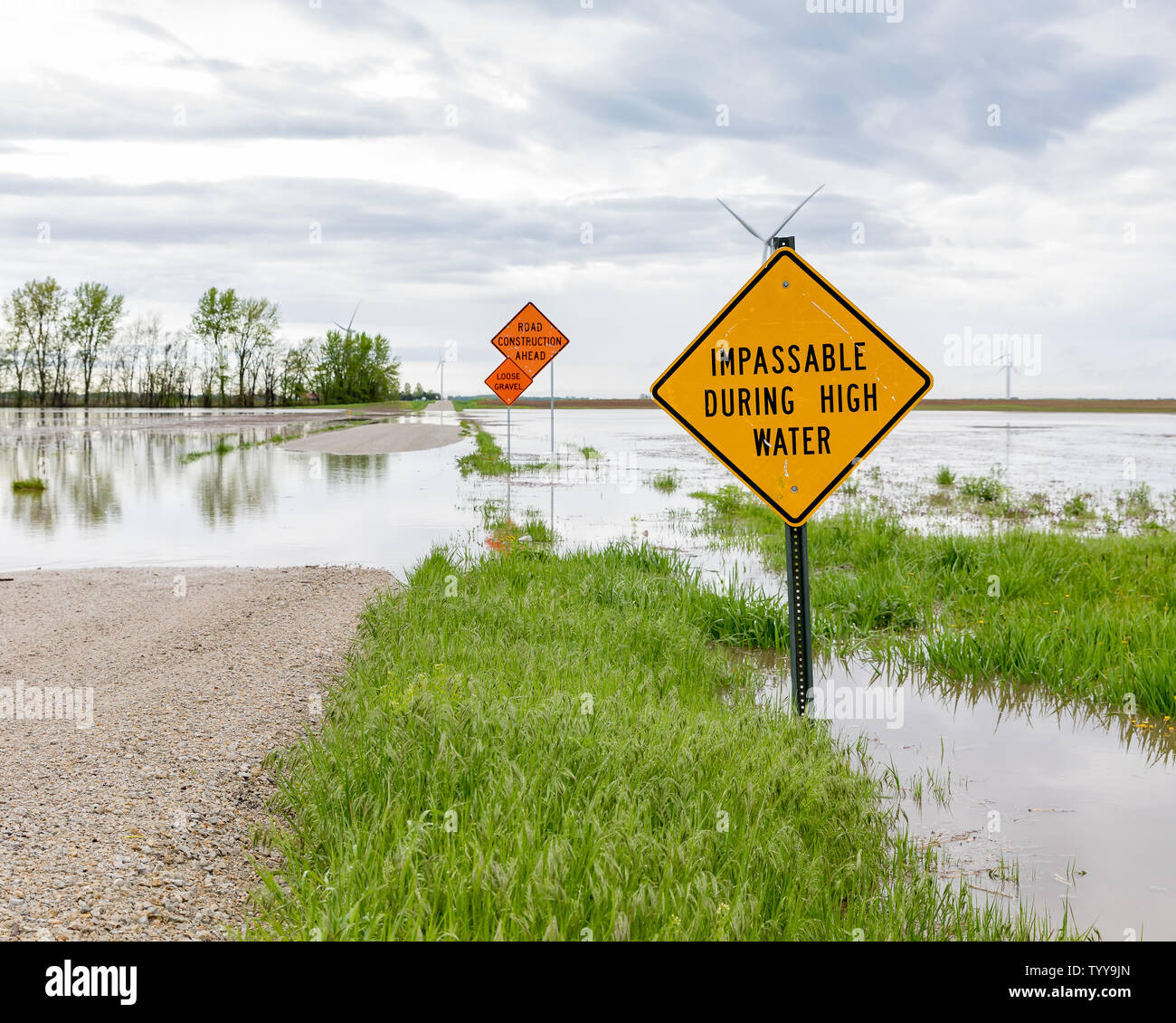 Water on pavement warning signs placed on road due to flooding from heavy rains and storms in the Midwest Stock Photo
