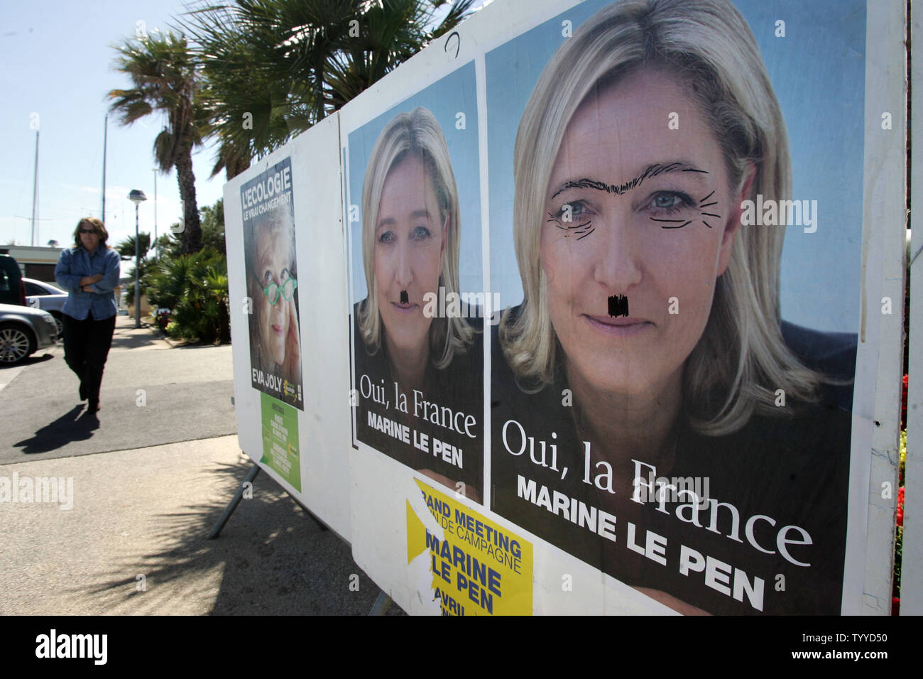 Wat dan ook interieur identificatie A woman walks past defaced campaign posters of ultra-right candidate Marine  Le Pen French people on the day of the first round of presidential  elections in the southern city of Hyeres, France,