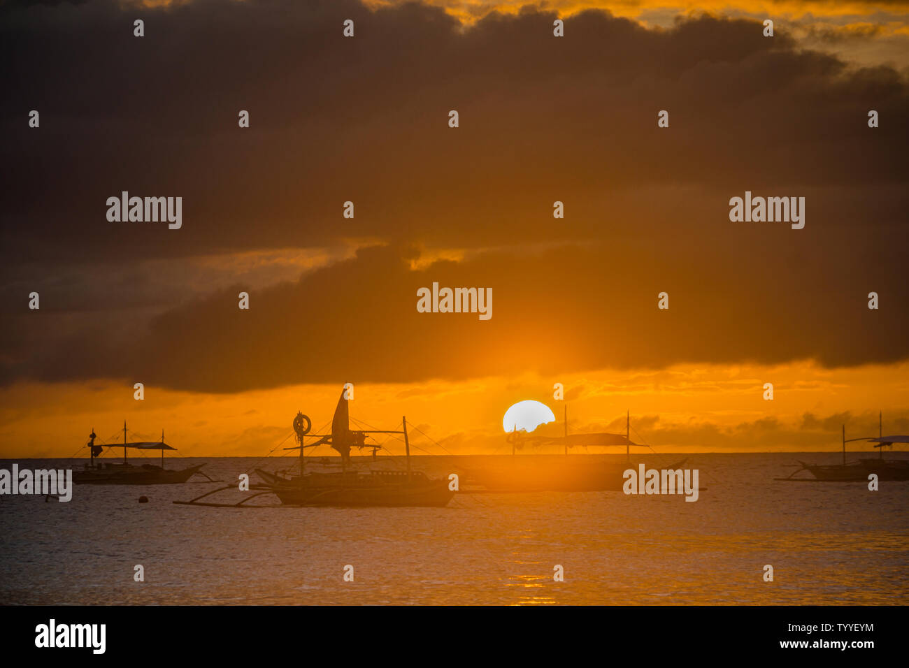Fishing boats are silhouetted by the sunset in Boracay, Philippines. Stock Photo