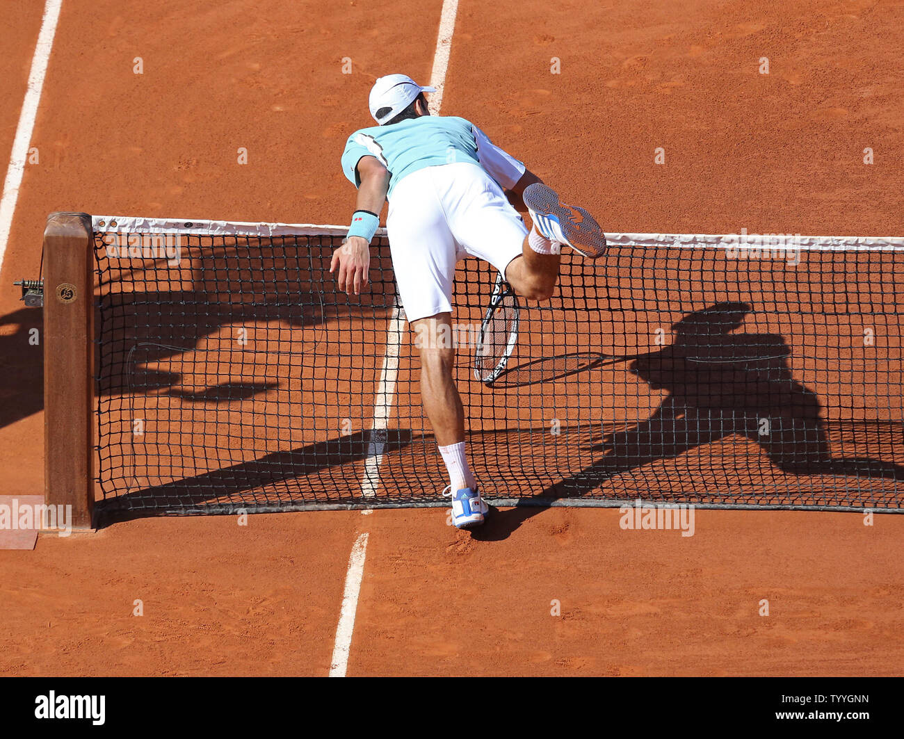 Serbian Novak Djokovic runs into the net after hitting a shot during his French  Open men's semifinal match against Spaniard Rafael Nadal at Roland Garros  in Paris on June 7, 2013. Nadal