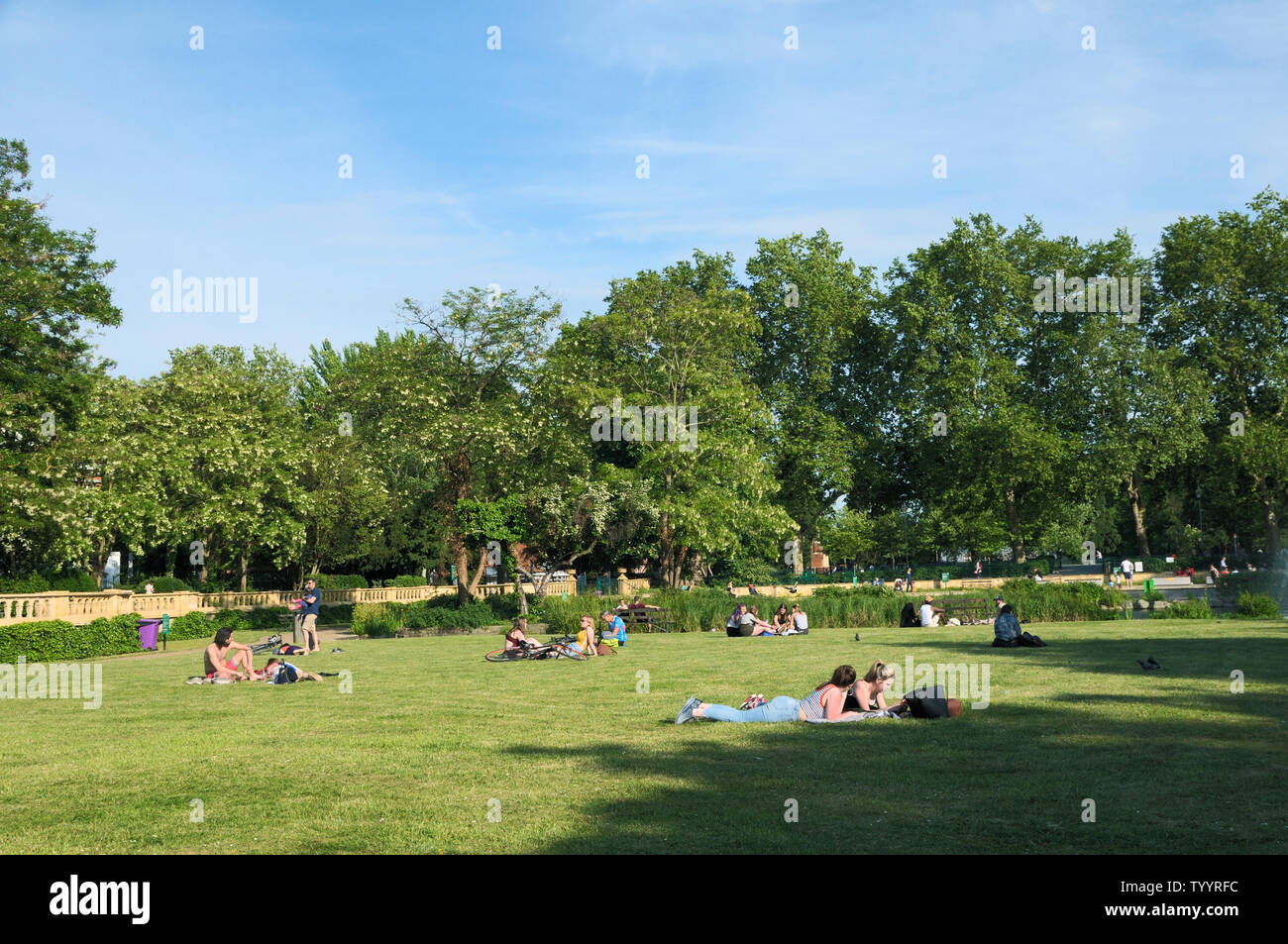 People relaxing in the sunshine at Bishops Park in Fulham, London, England, UK Stock Photo