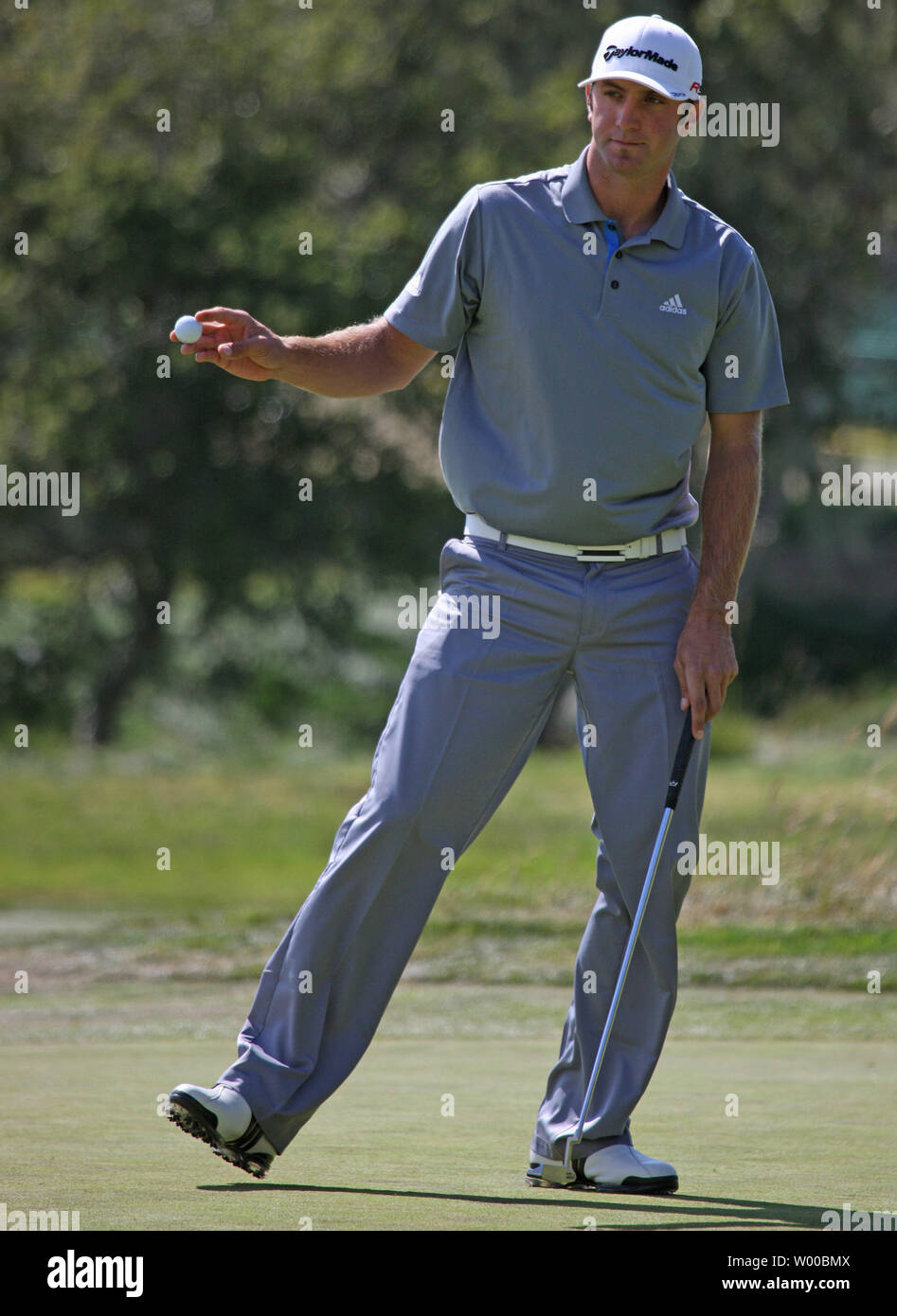 Dustin Johnson holds up the ball after par on the second hole on the