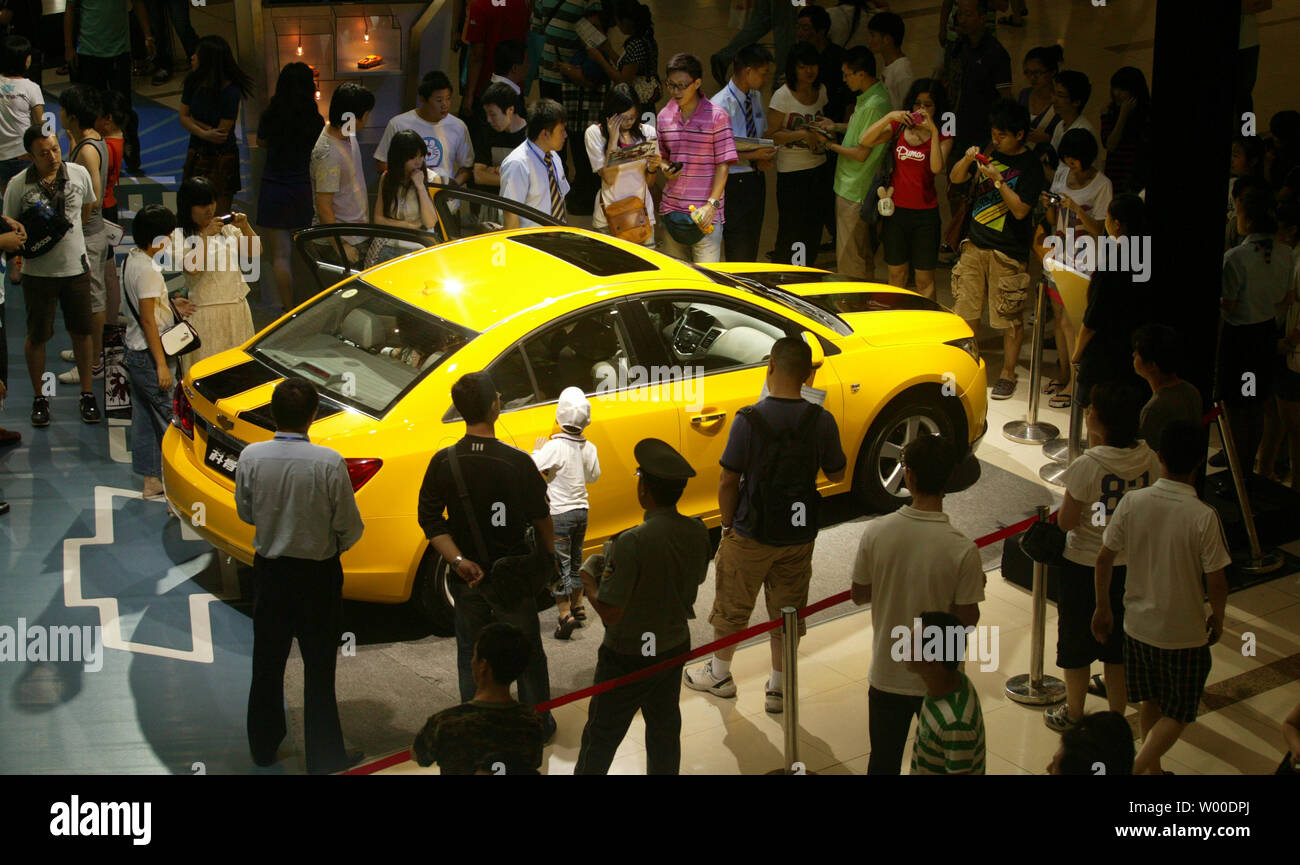 Chinese shoppers stop to look at a Chevrolet sports car promoting the soon-to-be released movie Transformers 2 at a shopping plaza in Beijing on June 22, 2009.  U.S. companies have begun to promote and advertise their products in China as they do in America over the last few years, especially as China's economy grows despite the global financial downturn.   (UPI Photo/Stephen Shaver) Stock Photo