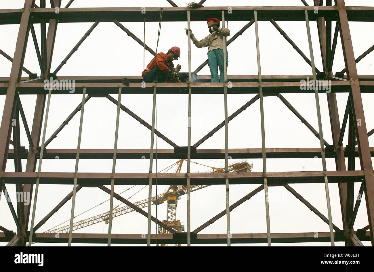 Chinese construction workers assemble steel scaffolding on an Olympic facility in central Beijing, August 2, 2006.  Officials are examining new steps to cool off China's sizzling economy as its top planning agency called for tighter bank credit and curbs on construction, state media reported.  The reports Wednesday suggested Beijing believes earlier measures, including an interest rate rise in April, are failing to contain runaway growth in spending on factories and other assets that Chinese leaders worry could ignite a financial crisis.  (UPI Photo/Stephen Shaver) Stock Photo
