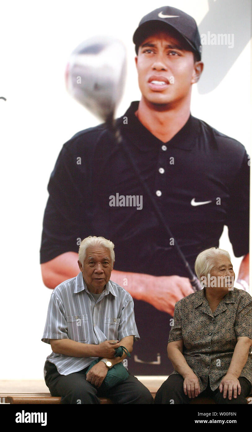 An Chinese couple sits in front of a giant photo of American golf superstar  Tiger Woods