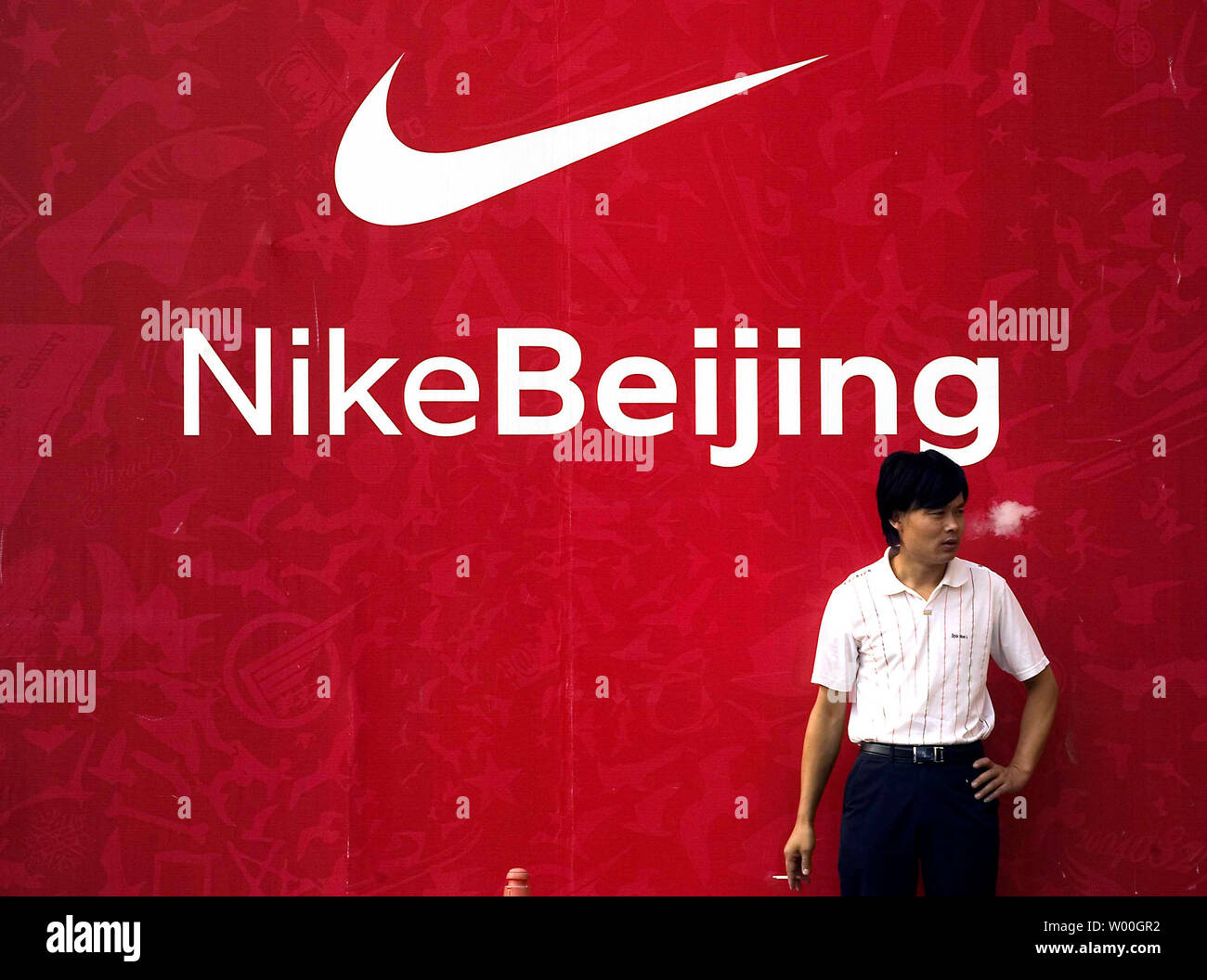 A Chinese man smokes a cigarette in front of a Nike advertisement outside a  shopping mall in Beijing, China on October 9, 2007. The Beijing 2008  Olympics are fast approaching and one
