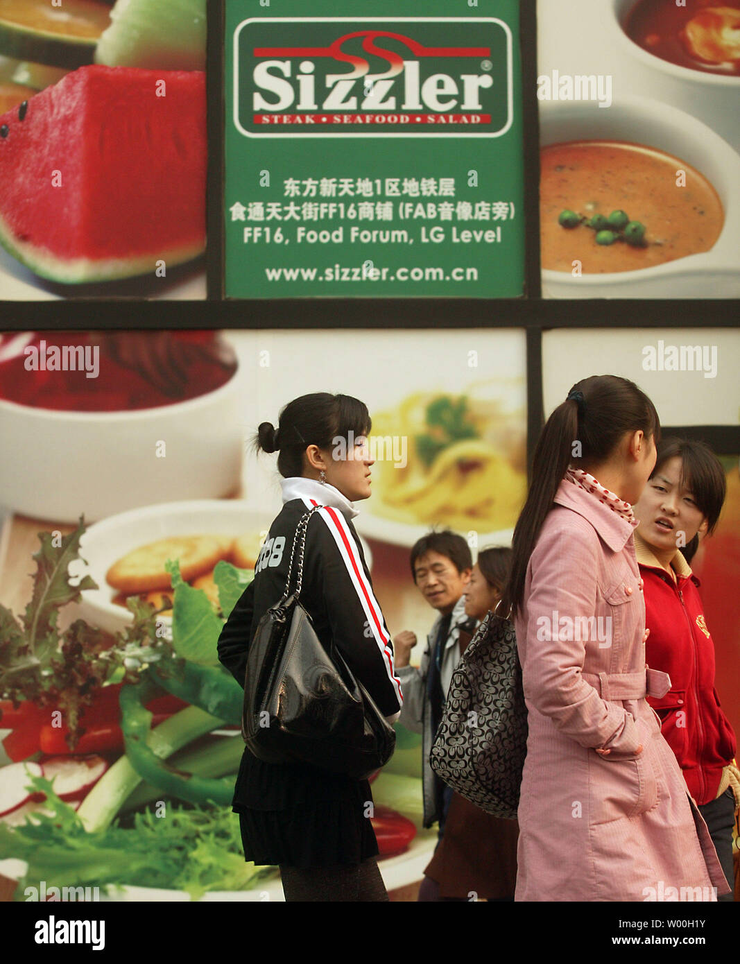 Chinese pedestrians walk past a U.S.-based Sizzler franchise in downtown Beijing, China on November 14, 2007.  Sizzler has joined the ranks of American icons such as McDonalds, Pizza Hut and Kentucky Fried Chicken that have established a strong presence in China.   (UPI Photo/Stephen Shaver) Stock Photo