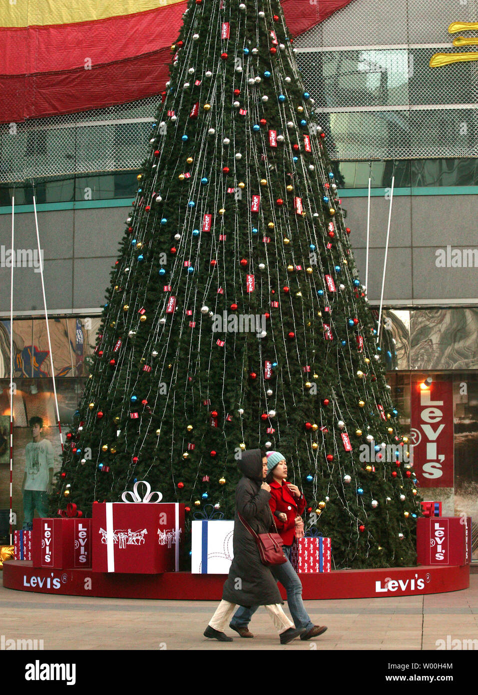 Chinese shoppers walk past a popular fashion shopping mall, adorned with a  Christmas tree by Levi's and decorated with a giant Coca-cola  advertisement, in Beijing, China on December 28, 2007. American-based  companies