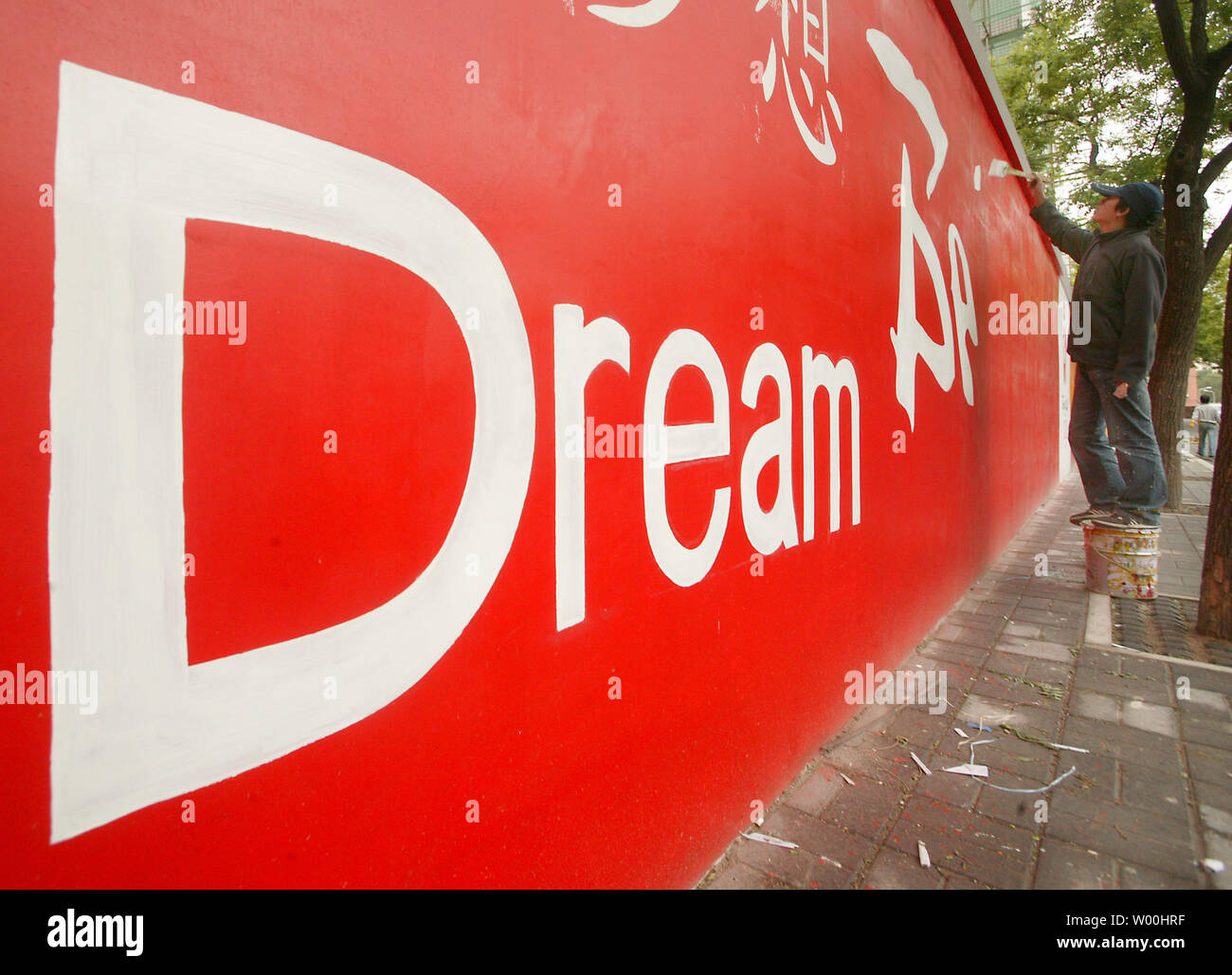 A Chinese artist paints Olympic logos and icons on a long concrete wall