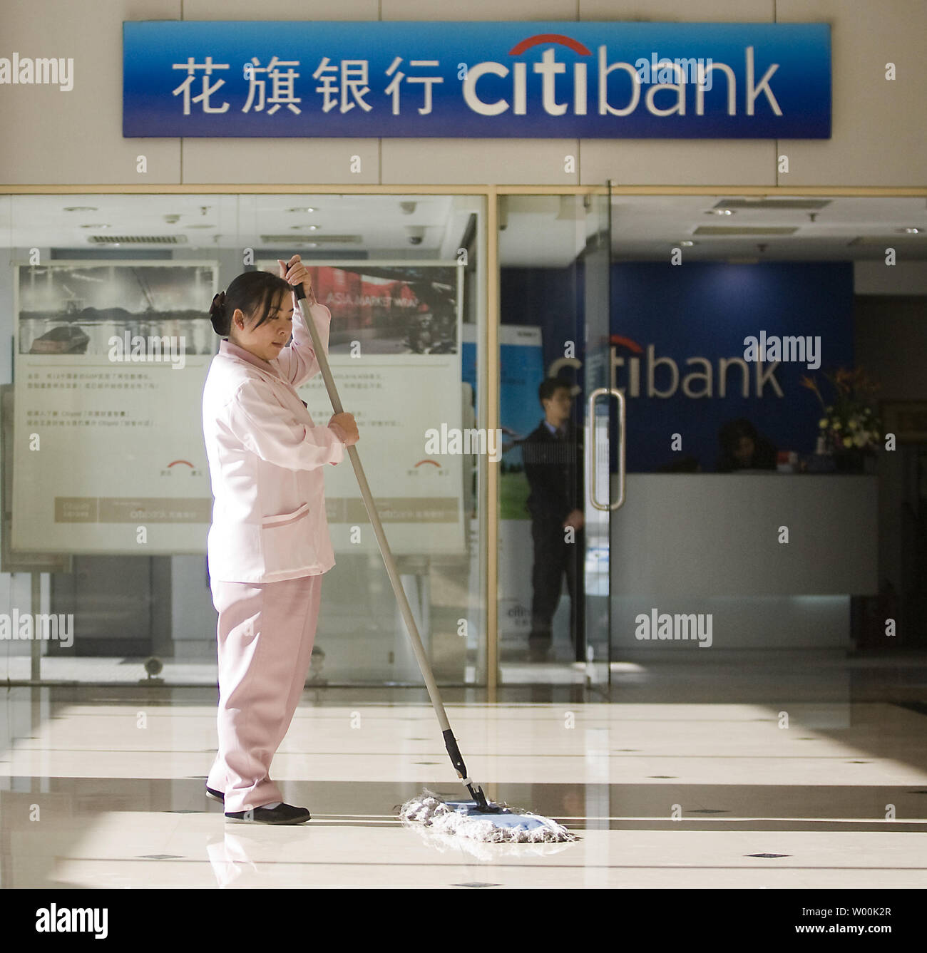 A Chinese janitor mops the lobby of a downtown Citibank branch in Beijing November 25, 2008. Asia Pacific shares rose on Tuesday thanks to Wall Street's overnight rally in relief at the Citibank's $300bn bailout.   (UPI Photo/Stephen Shaver) Stock Photo