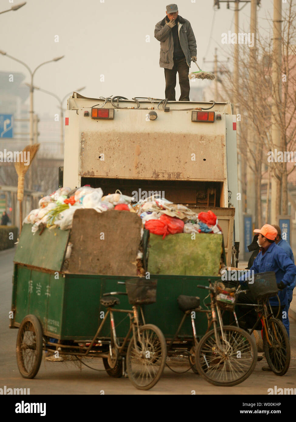 A Chinese man cleans the top of his garbage truck while stopped to collect neighborhood trash in central Beijing February 03, 2009.  The global economic slowdown that has hit the stock markets has struck the trash markets too. Commodity prices for recycled metals and papers took sharp dives last fall as demand for them in China and elsewhere slackened. (UPI Photo/Stephen Shaver) Stock Photo