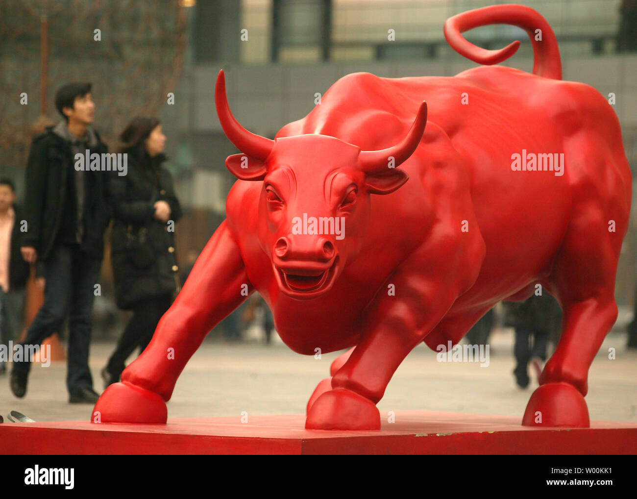 A Chinese couple walks past a public sculpture of a red bull, displayed in  celebration of the Lunar New Year and the beginning of the Year of the Ox,  in Beijing February