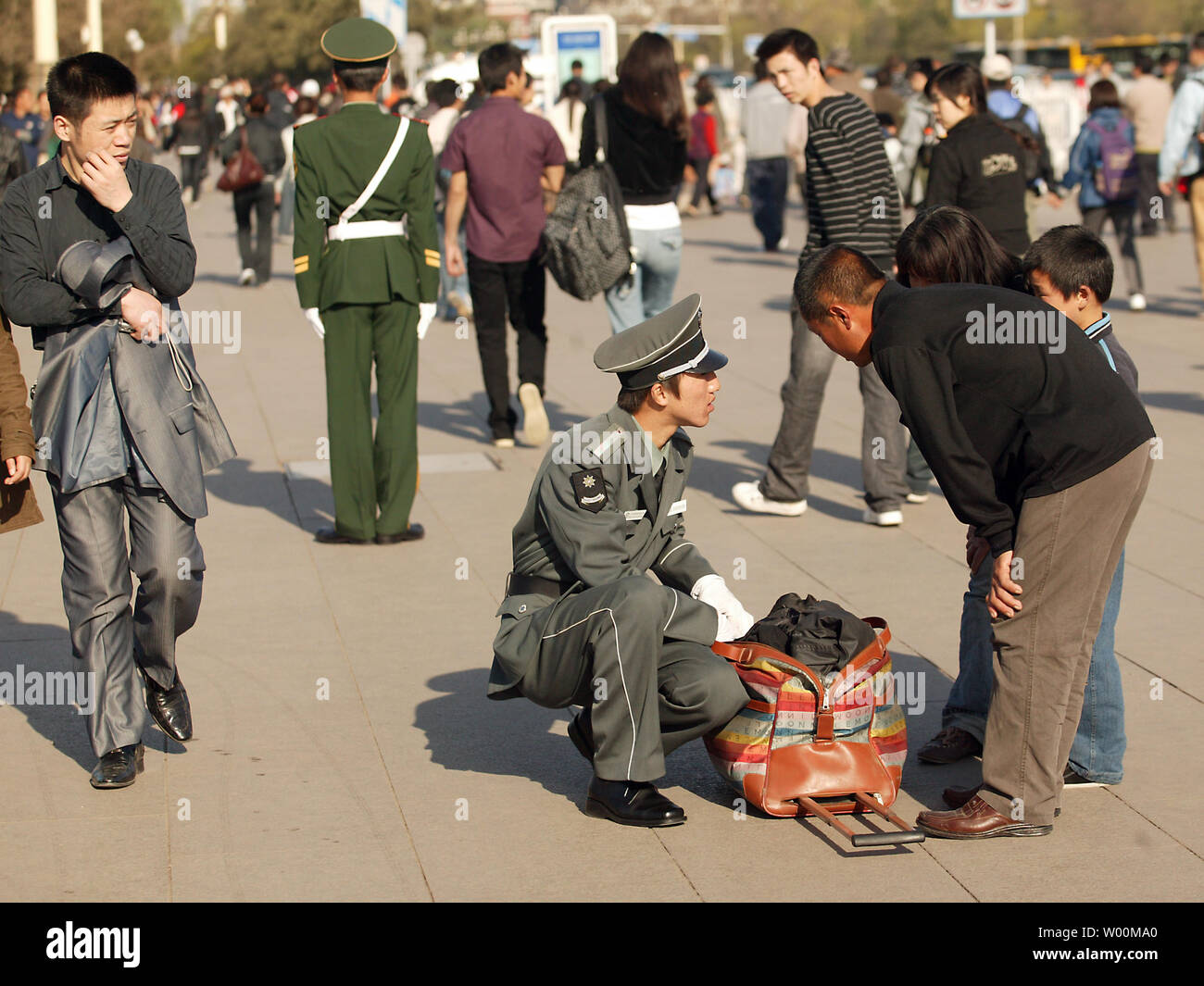 A Chinese security guard checks a family&rsquo;s belongings on Tiananmen 
