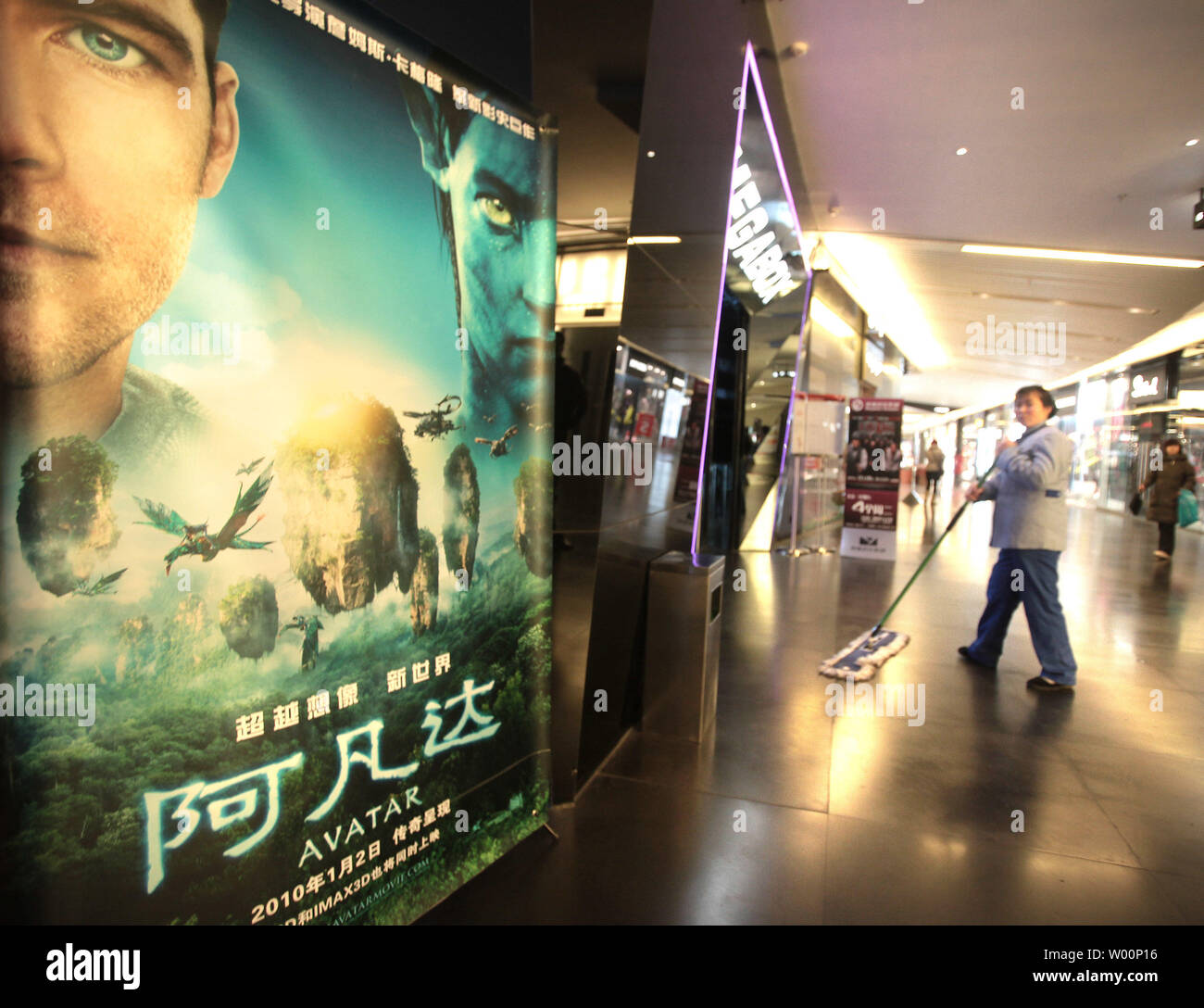 A Chinese janitor mops the floor outside a movie theater, showing the new  blockbuster 