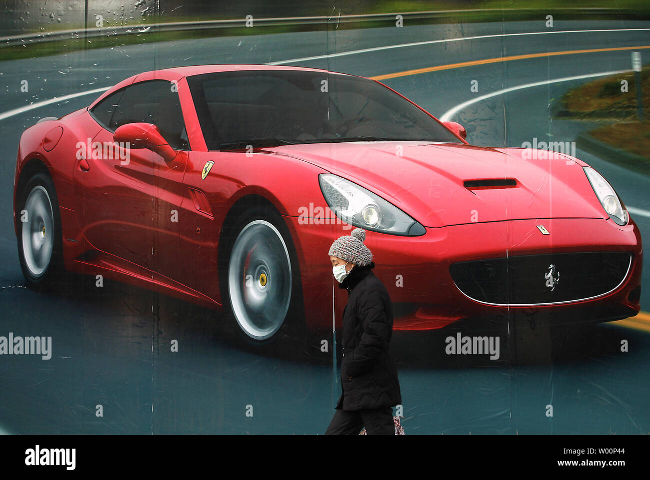 A Chinese woman walks past an advertisement for Ferrari sports cars in Beijing on February 4, 2010.  In a research carried out by Hurun, a company that has tracked China's rich and famous for 11 years, billionaires and multimillionaires each spend close to 2.2 million yuan (USD322,000) a year on living the high life in the capital. The report show more than cent of Beijing's richest people own between two and five luxury cars. Their average age was just 38.7.     UPI/Stephen Shaver Stock Photo
