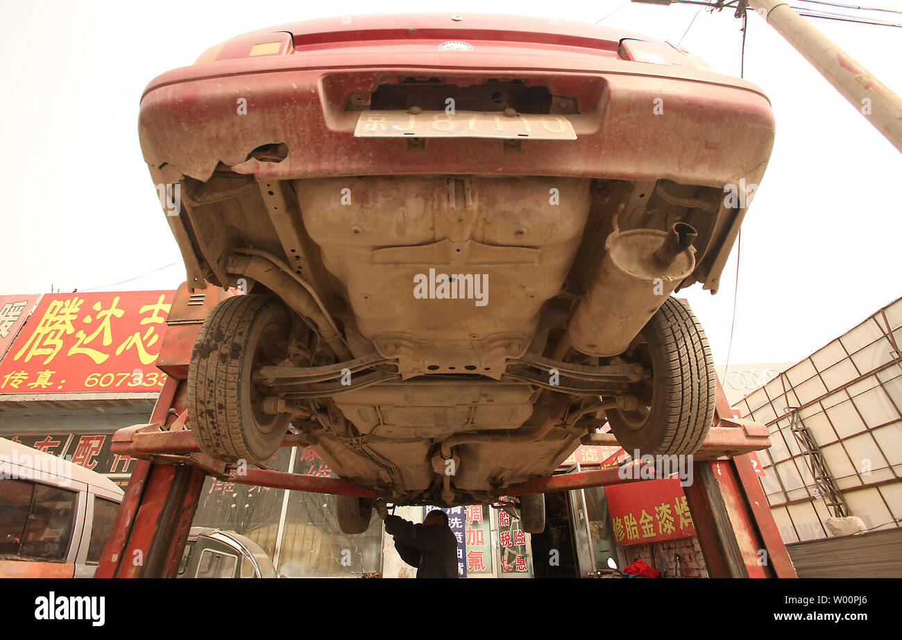 A Chinese Automobile Mechanic Works On A Car At A Low Tech