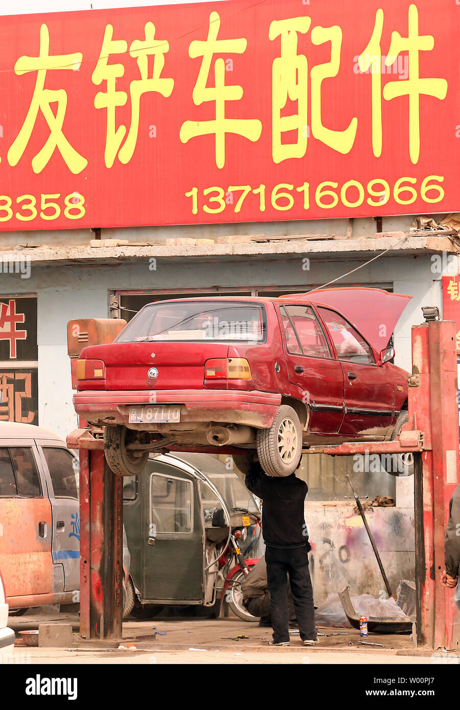 A Chinese Automobile Mechanic Works On A Car At A Low Tech