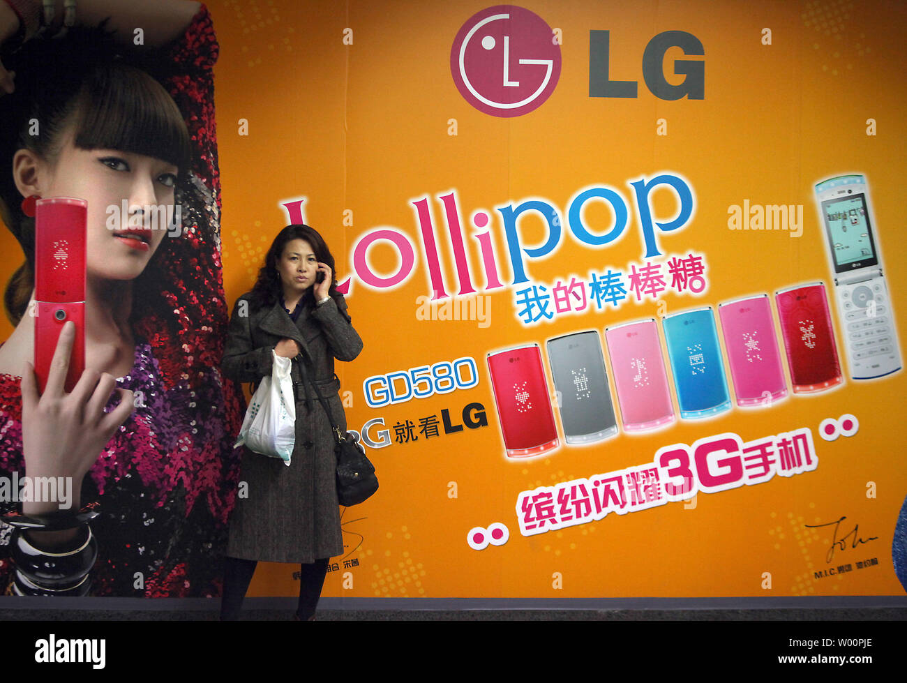 A Chinese woman talks on her mobile phone in front of a large advertisement for a new series of phones in Beijing on March 30, 2010.  China stands now as the biggest market of mobile phone sales in the world.    UPI/Stephen Shaver Stock Photo