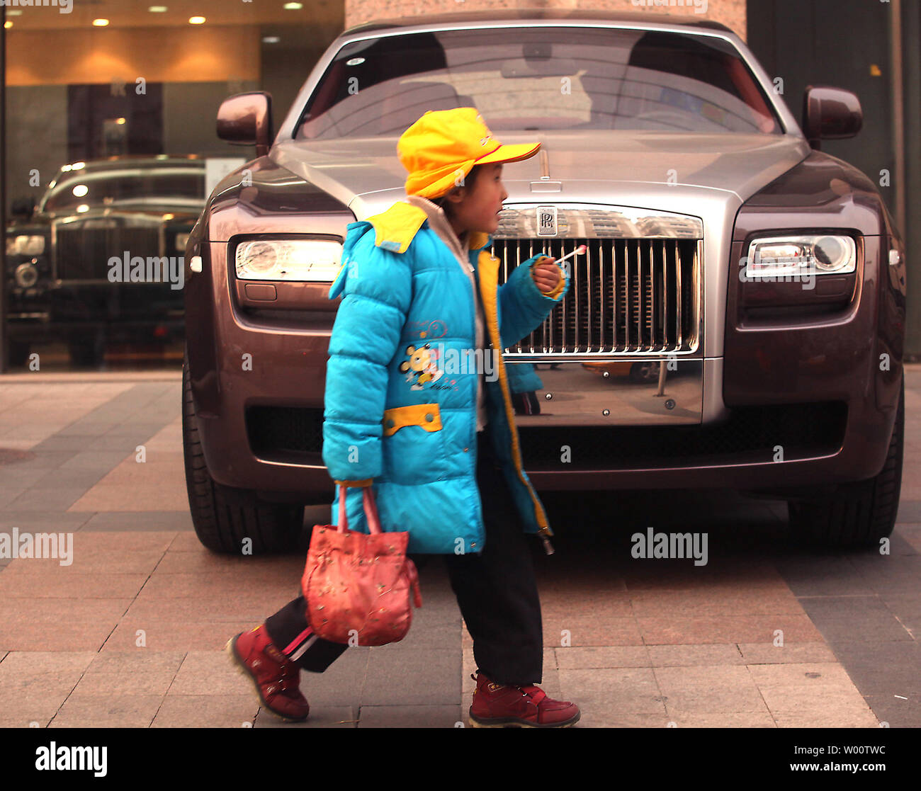 A young Chinese student walks past Rolls-Royce's flagship showroom in downtown Beijing December 12, 2010.  While in traditional markets luxury car makers might still be feeling the effects of the global financial crisis of 2008, in China things have never been better with astonishing growth figures being recorded as the nation's new wealthy treat themselves to the world's most high-end-modes of transport.     UPI/Stephen Shaver Stock Photo