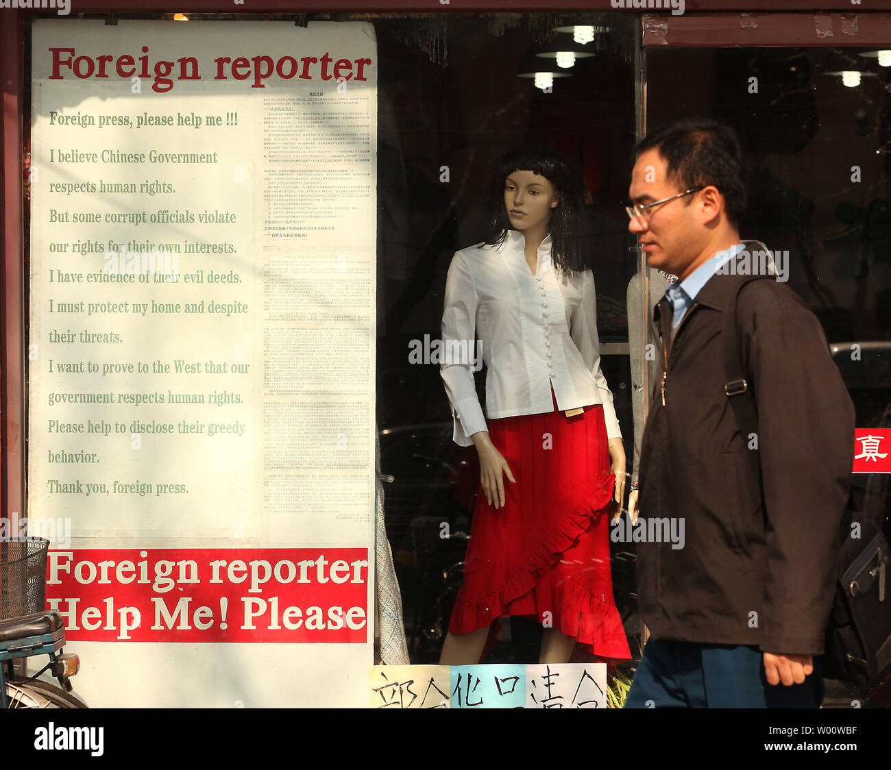 A Chinese man walks past a clothing store advertising a plea for help to foreign journalists for help against local corruption in Beijing February 22, 2011.  China must find new ways to defuse unrest, the country's  domestic security chief said this week, underscoring the capital's anxiety about control after police quashed calls for gatherings inspired by uprisings in the Middle East.     UPI/Stephen Shaver Stock Photo