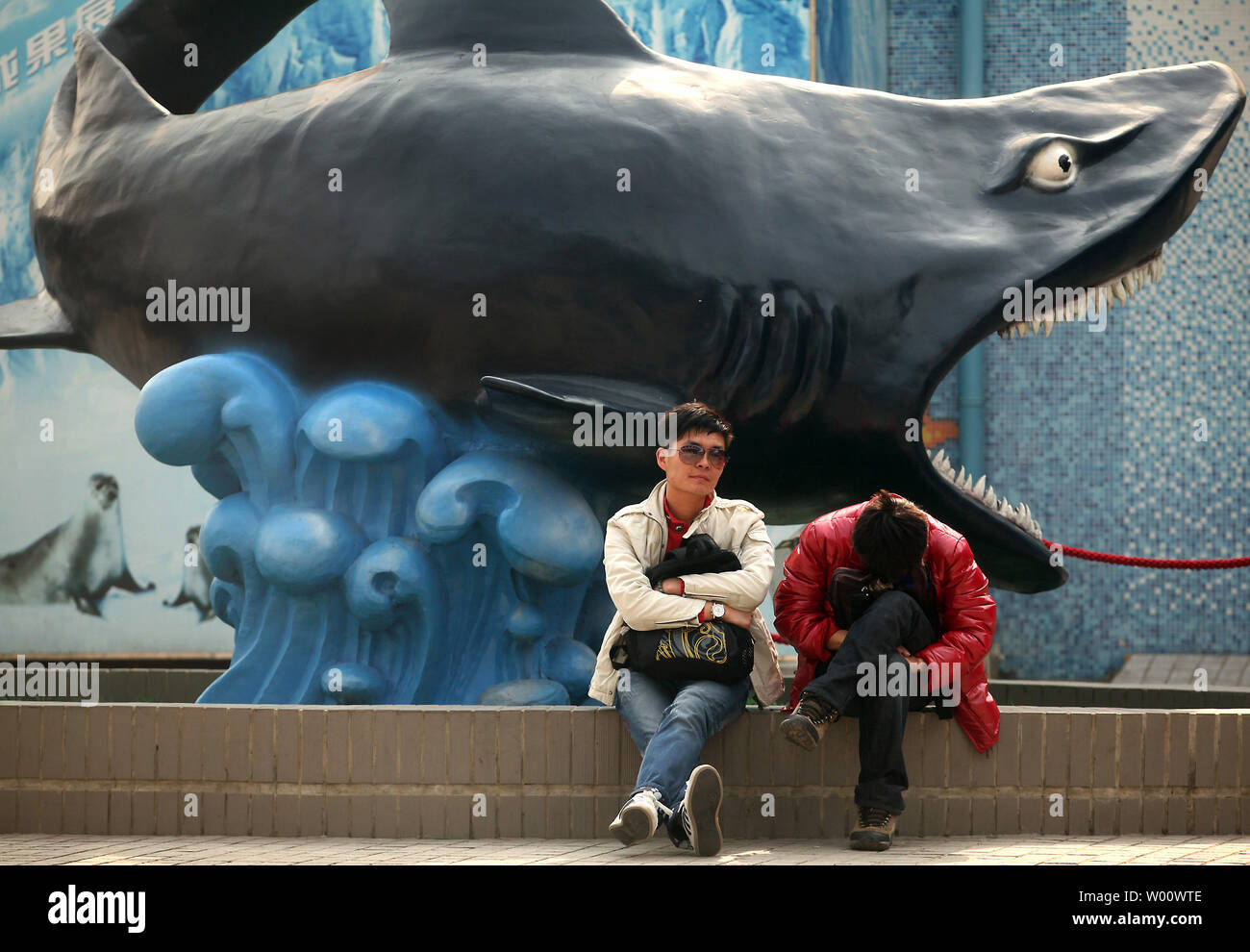 Chinese men wait outside Beijing's Blue Zoo aquarium, the largest of its  type in Asia, on March 31, 2011. The aquarium's main tank holds 3.5 million  liters of artificially produced salt water