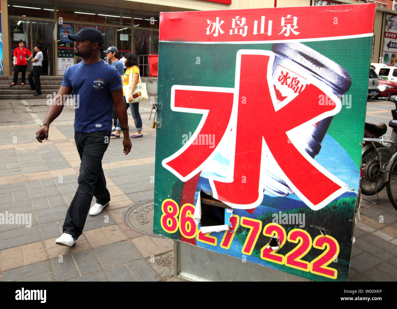 A foreigner walks past advertisement for bottled water outside a supermarket in Beijing July 15, 2011. Authorities in China's capital have halted the sale of 31 brands of bottled water  after they failed safety tests, the government reported, in the latest scare to hit China.    UPI/Stephen Shaver Stock Photo