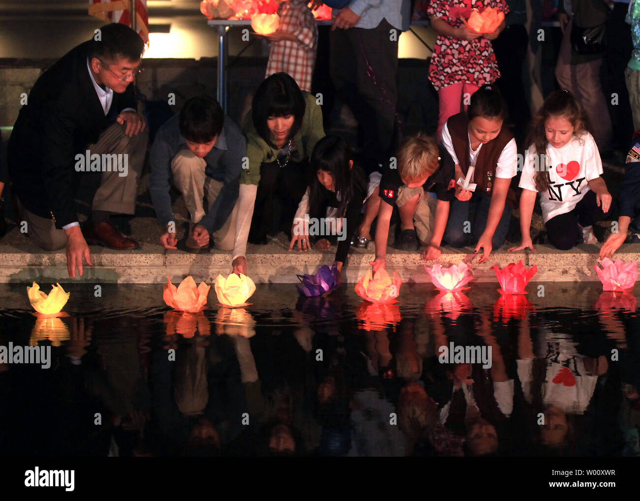 New U.S. Ambassador to China Gary Locke (L) and American guests place floating candles onto a reflecting pool to pay respects to the victims of the 9/11 attacks during a memorial service on the grounds of  the U.S. embassy in Beijing on September 11, 2011.   Sunday marks the 10th anniversary of the 9/11 attacks that brought down the World Trade Center towers in New York.      UPI/Stephen Shaver Stock Photo