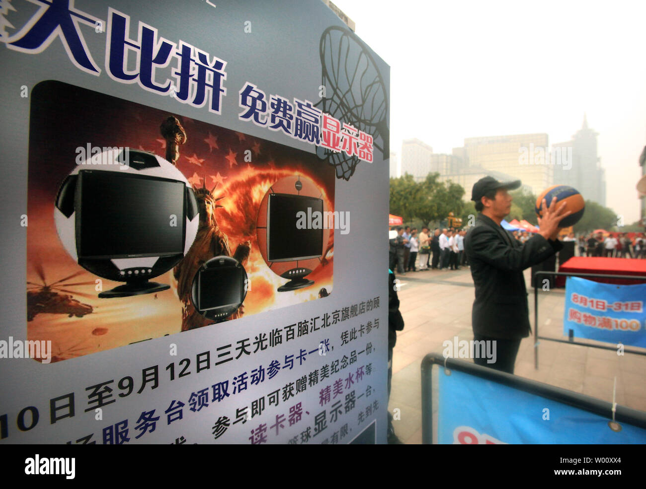 A Chinese migrant worker tries his hand at shooting hoops for a chance to win inexpensive gifts at an electronics fair promoting computer sales coinciding with students returning to school in Beijing on September 12, 2011.  Some of the stalls used images of American icons of liberty and war to advertise their goods.     UPI/Stephen Shaver Stock Photo