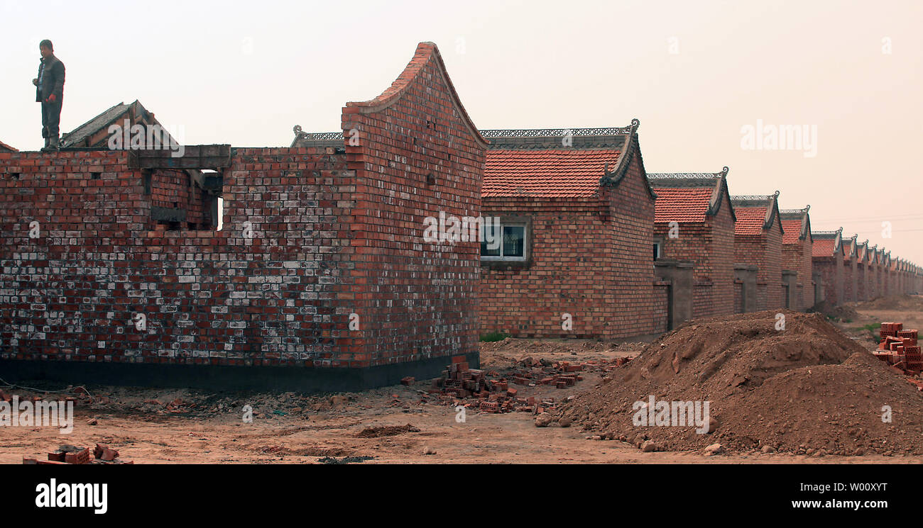 Relocated, poor rural farmers, under the direction of the Ningxia Ecological Migration Program, build a small village for resettlement in Yongning County, a frontier area in the northwestern province Ningxia Hui Autonomous Region on September 23, 2011.  Ningxia has built 25 migration settlements since 1983, allocating over 55,000 hectares of arable land to 412,000 poverty-stricken farmers.  The government-sponsored partial migration project to relocate poor farmers living in the arid and frigid southern mountains to the Yellow River irrigation areas is aimed at fundamentally changing and impro Stock Photo