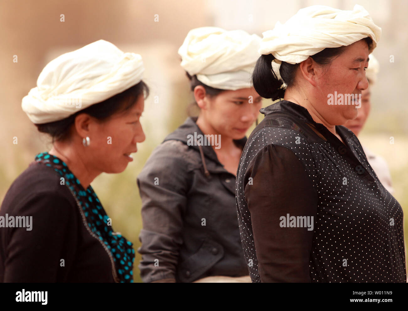 Chinese ethnic minority muslim women watch a roadside burial ritual of a member of their village in Lijiang, northern Yunnan Province, on September 30, 2012.   China recognizes 55 ethnic minority groups within the country in addition to the Han majority.  With over 25 ethnic minorities living in Yunnan, they make up about 34 percent of its population.  All are hanging on their cultural identity as 'progress' is accompanied by a larger, more powerful Han majority.      UPI/Stephen Shaver Stock Photo