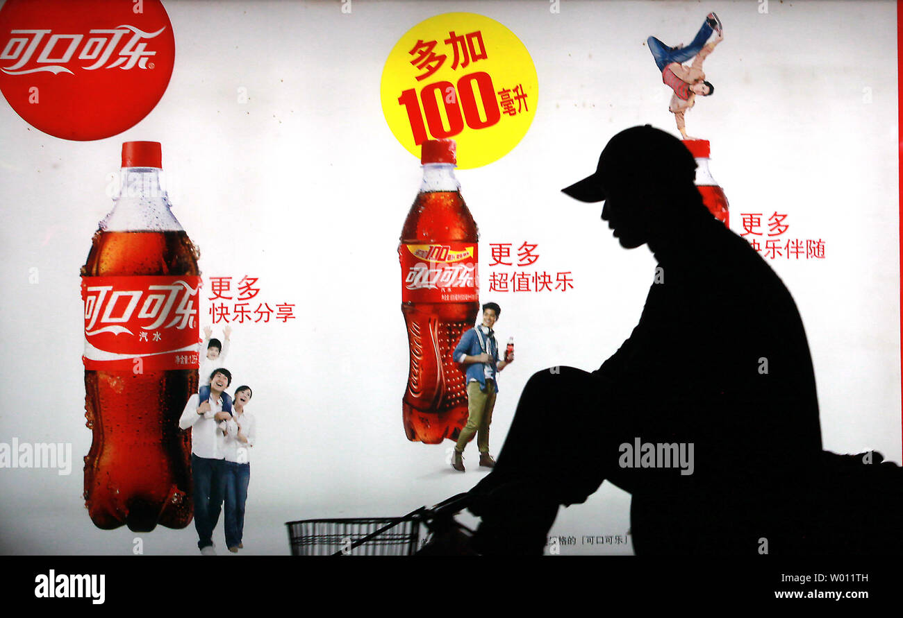 A Chinese man rides past a billboard advertising Coca-Cola soft drinks on the streets of Beijing on October 23, 2012.  Last week Coca-Cola said that sales in China grew an anemic 2% compared to 11% last year.  Shares of the world's largest beverage company lost more than 2% this month, mainly due to the slowing of China's economy.      UPI/Stephen Shaver Stock Photo