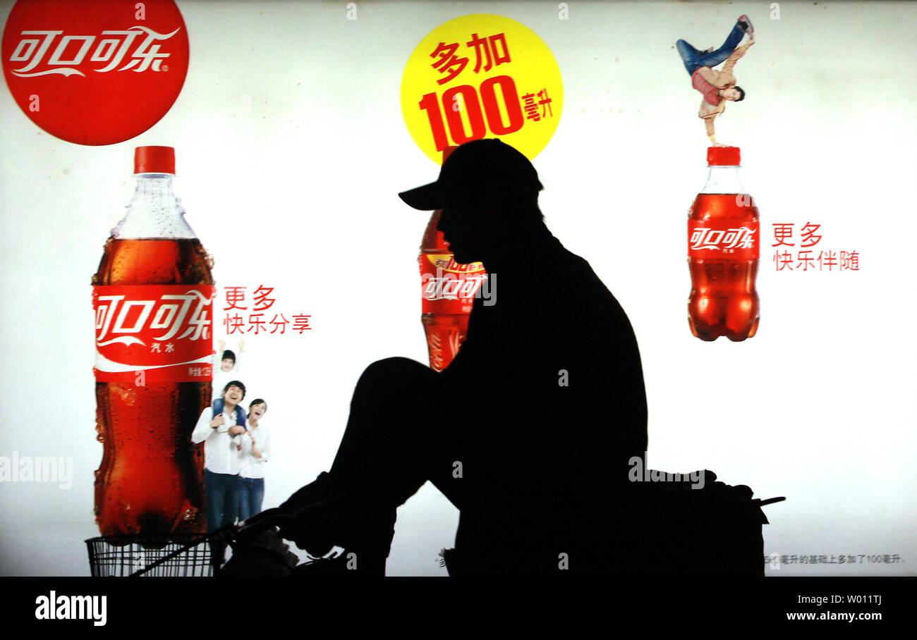 A Chinese man rides past a billboard advertising Coca-Cola soft drinks on the streets of Beijing on October 23, 2012.  Last week Coca-Cola said that sales in China grew an anemic 2% compared to 11% last year.  Shares of the world's largest beverage company lost more than 2% this month, mainly due to the slowing of China's economy.      UPI/Stephen Shaver Stock Photo