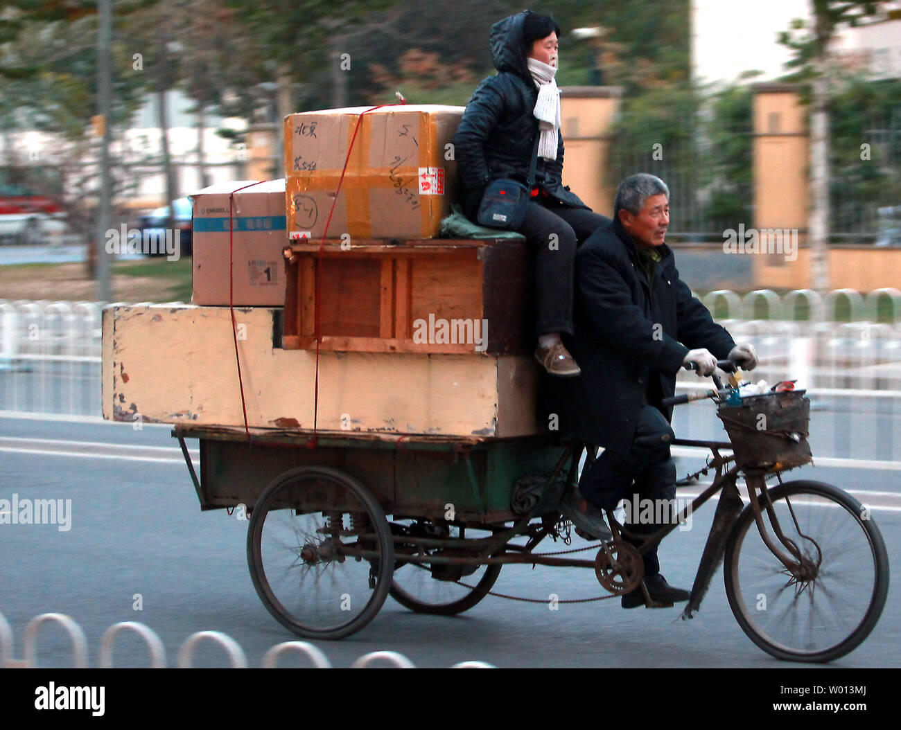 A Chinese couple transports old furniture on their 3-wheel wagon in downtown Beijing on November 16, 2013.  China, one of the world's fastest  growing countries and economies over the past three decades, is facing a long-term decline in its economic growth rate, according to a top Chinese economic  and political strategist .        UPI/Stephen Shaver Stock Photo