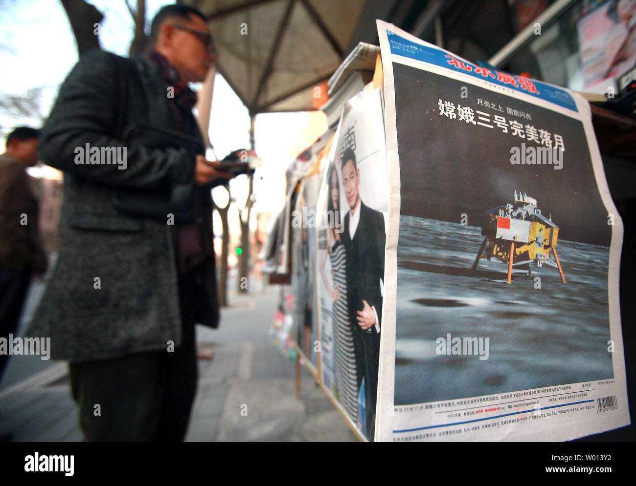 China's lunar landing is run on the front page of leading Chinese newspapers being sold at a news stand in Beijing on December 15, 2013.  China joined elite company yesterday with the controlled landing of its 'Jade Rabbit' rover on the moon.  China follows the U.S. and Soviet Union as the third country with a controlled - or 'soft' -  landing on the moon's surface.        UPI/Stephen Shaver Stock Photo