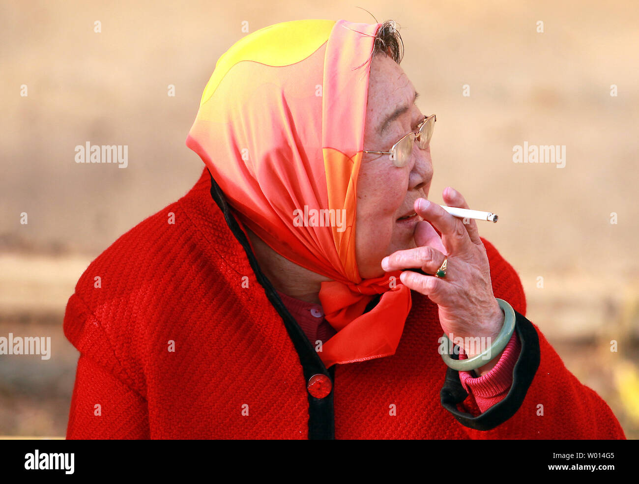 An elderly Chinese woman smokes a cigarette in Beijing on March 4, 2014.  China needs to take a firmer stance against its powerful tobacco industry if it hopes to reduce the roughly 1 million smoking-related deaths the country sees every year, according to the World Health Organization.      UPI/Stephen Shaver Stock Photo