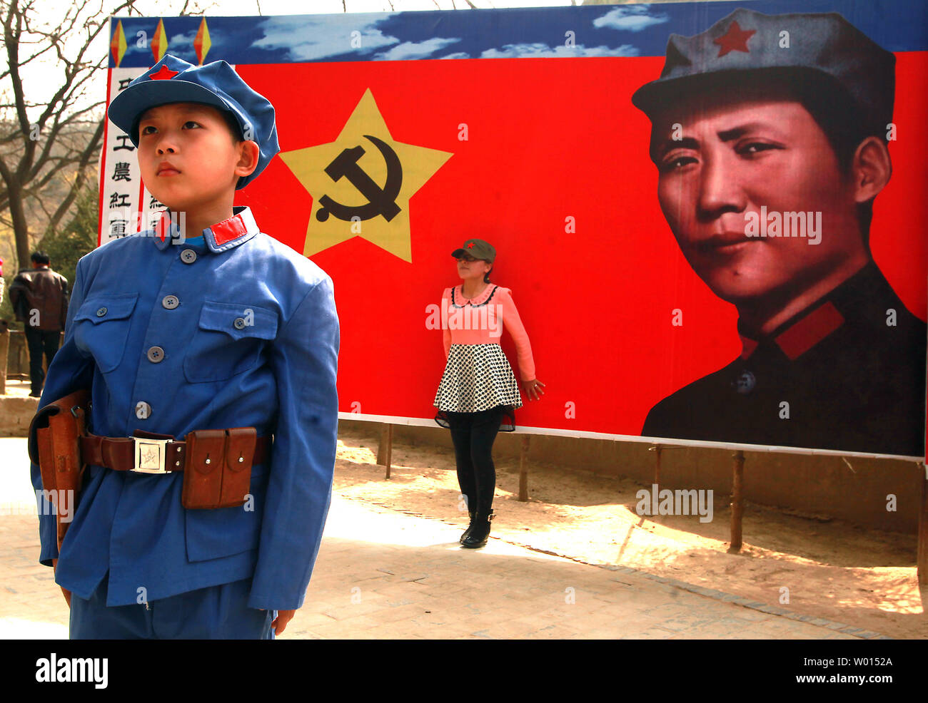 A Chinese boy dressed in a communist uniform poses for a photo, in front of a banner of the communist party's ideal soldier Li Feng, at a site used by former helmsman Mao Zedong and other leaders to discuss policy and future strategies in the Yangjialing Revolution, in Yan'an, Shaanxi Province, on April 6, 2014. Yan'an was close to the endpoint of the Long March, and became the center of the Chinese Communist revolution led my Mao from the 1936 to 1948. Chinese communists celebrate the city as the birthplace of modern China and the cult of Mao. UPI/Stephen Shaver Stock Photo