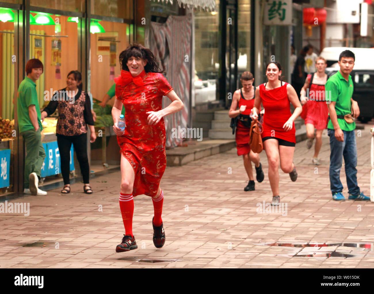 Foreigners and Chinese, both men and women, wear red dresses while running  through the streets of Beijing for the annual Red Dress Run for Charity on  June 8, 2014. The event will