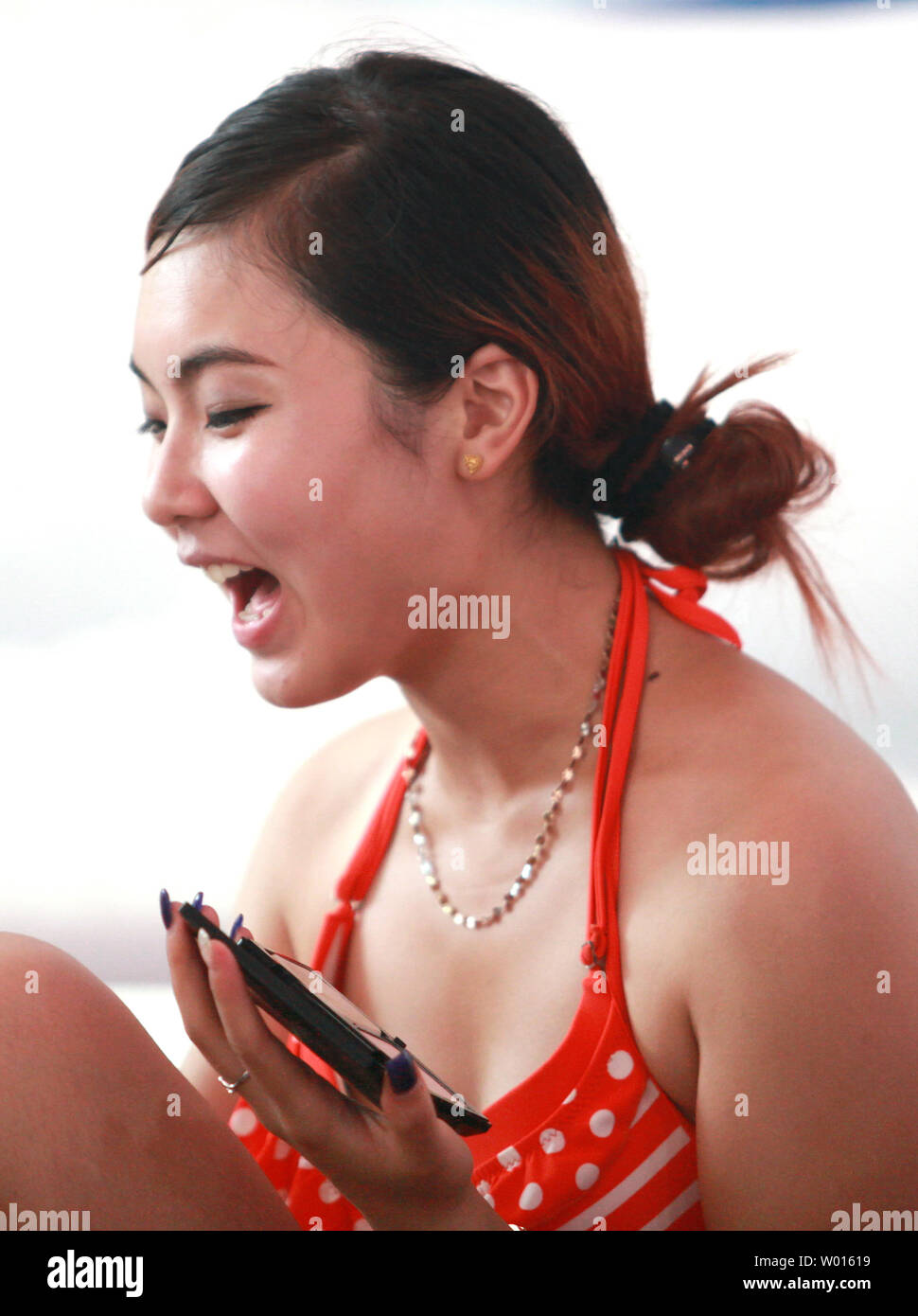 A Chinese model reacts to being named a finalist in a fashion show contest on a beach in the coastal city Qingdao, a major port in eastern Shandong Province, on August 19, 2014.  Modeling has become a new, fast avenue for young Chinese women to earn money and travel as competition for menial and professional jobs increases across China.     UPI/Stephen Shaver Stock Photo