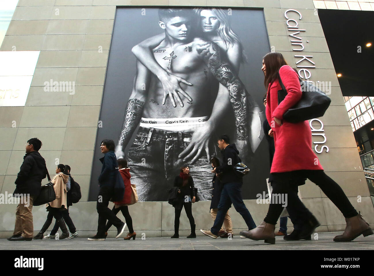 Chinese shoppers walk past a newly opened Calvin Klein clothing boutique in  Beijing on March 18, 2015. American and European clothing brands continue  to expand in China in hopes of tapping into