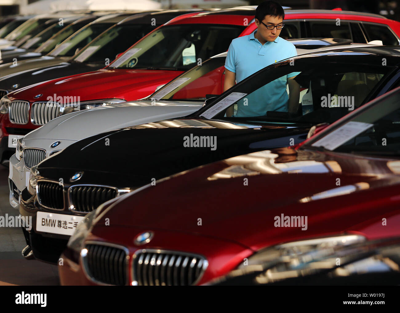Chinese check out a row of new BMWs on display and for sale at a plaza