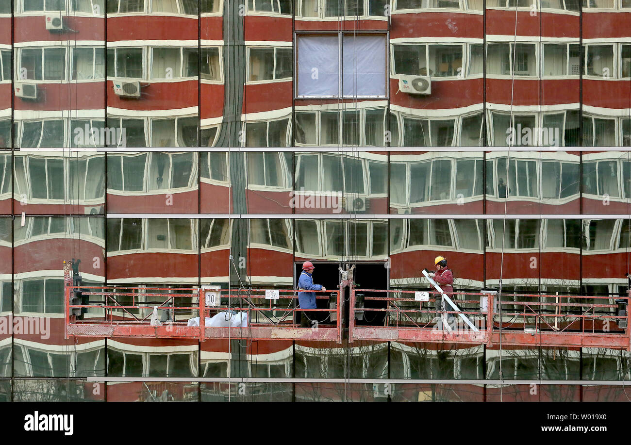 An old residential building is reflected in the facade of a new, international hotel being built in downtown Beijing on January 3, 2016.  China's growth looked set for a slow start to 2016 after activity in the manufacturing and construction sectors contracted for a fifth straight month in December, indicating the government may have to step up economic support to avert a sharper slowdown.     Photo by Stephen Shaver/UPI Stock Photo