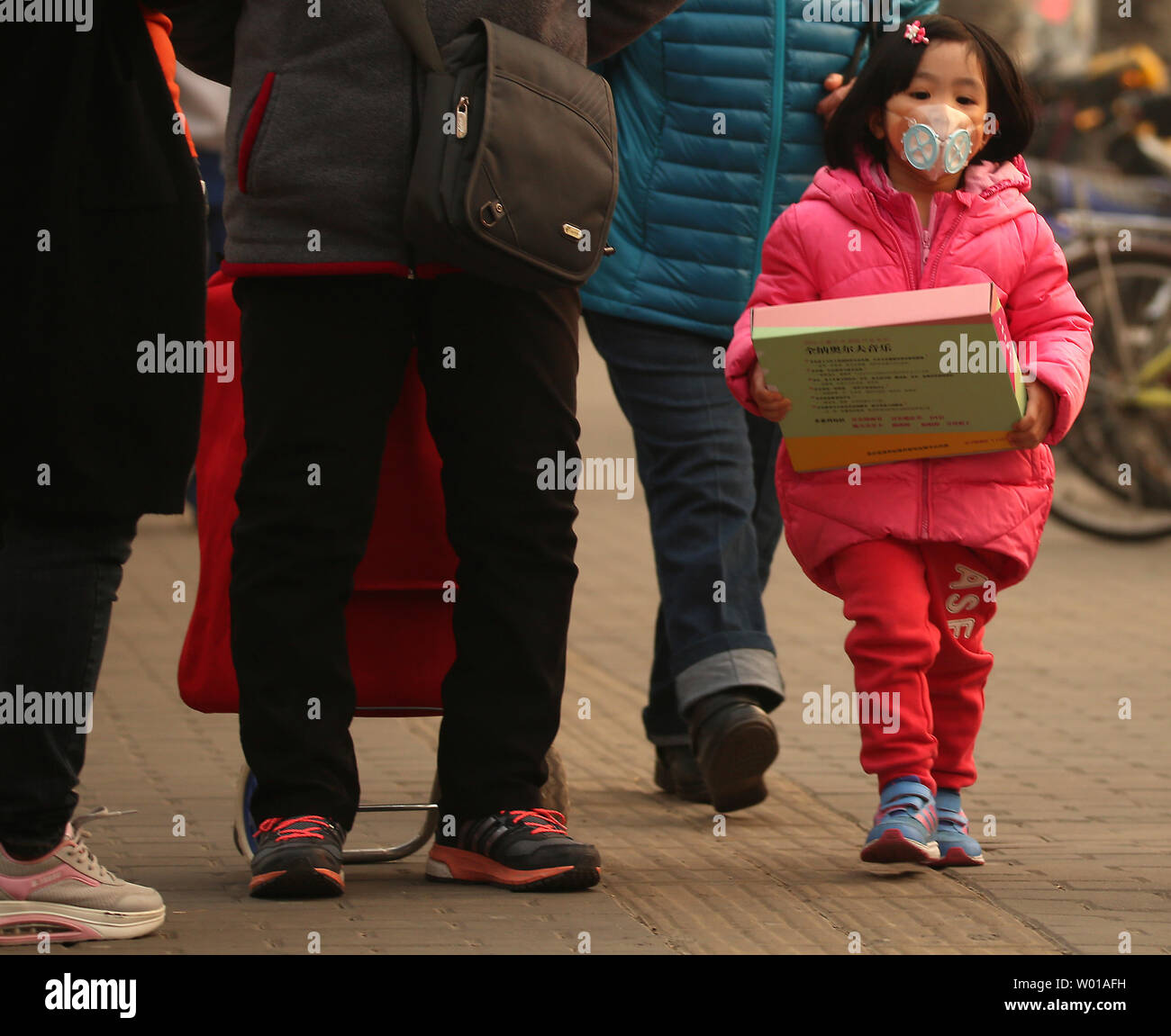 A young Chinese girl wears an air filter mask while walking with her parents in Beijing on March 10, 2016.  China will intensify its efforts to reduce air pollution, citing as an example ambitious targets in fighting smog that will increase the number of days with good air quality.      Photo by Stephen Shaver/UPI Stock Photo
