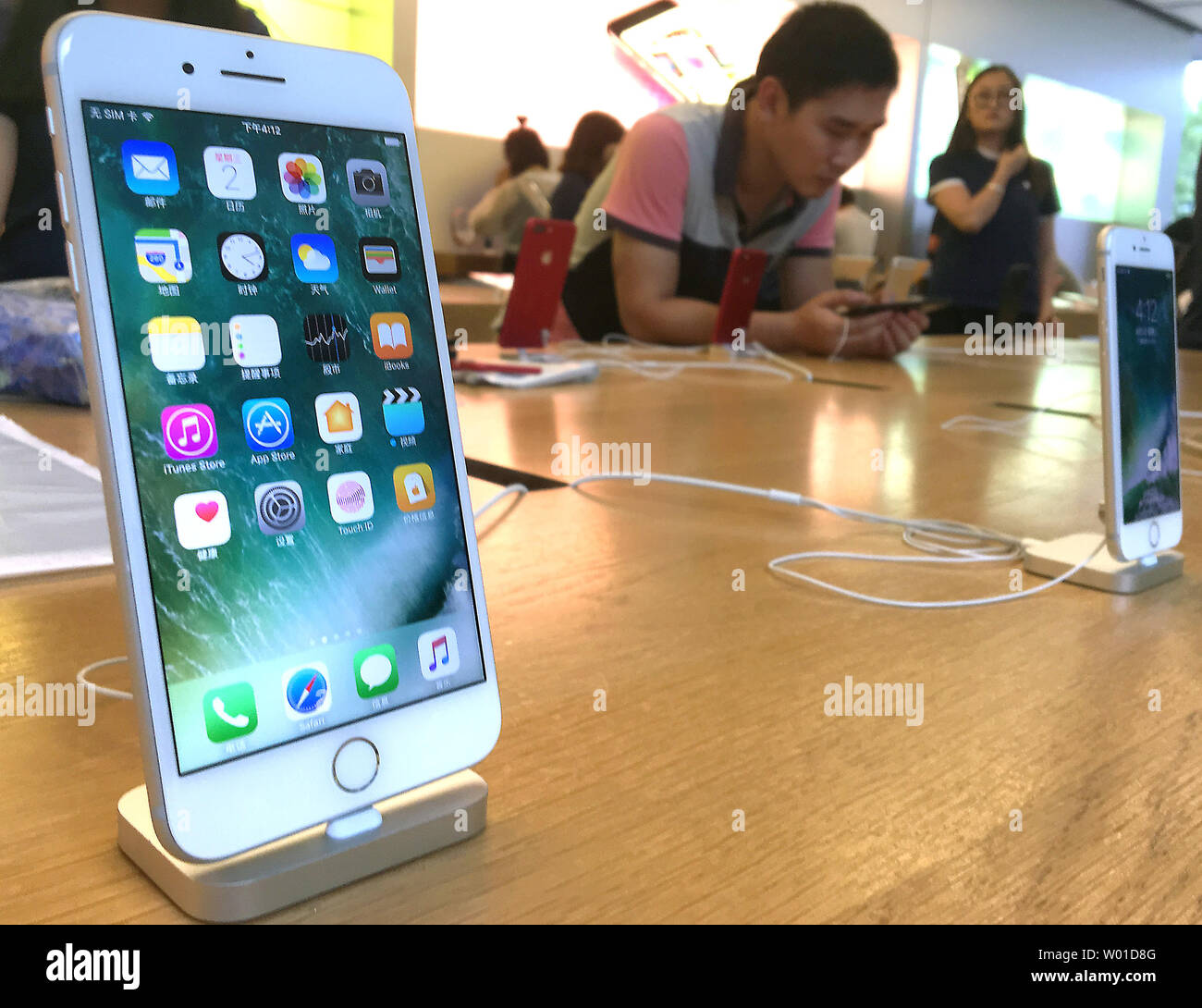 Chinese look at iPhones on display in Beijing's flagship Apple store on  August 2, 2017. Apple boss Tim Cook has defended his company's decision to  comply with the Chinese government's demand it