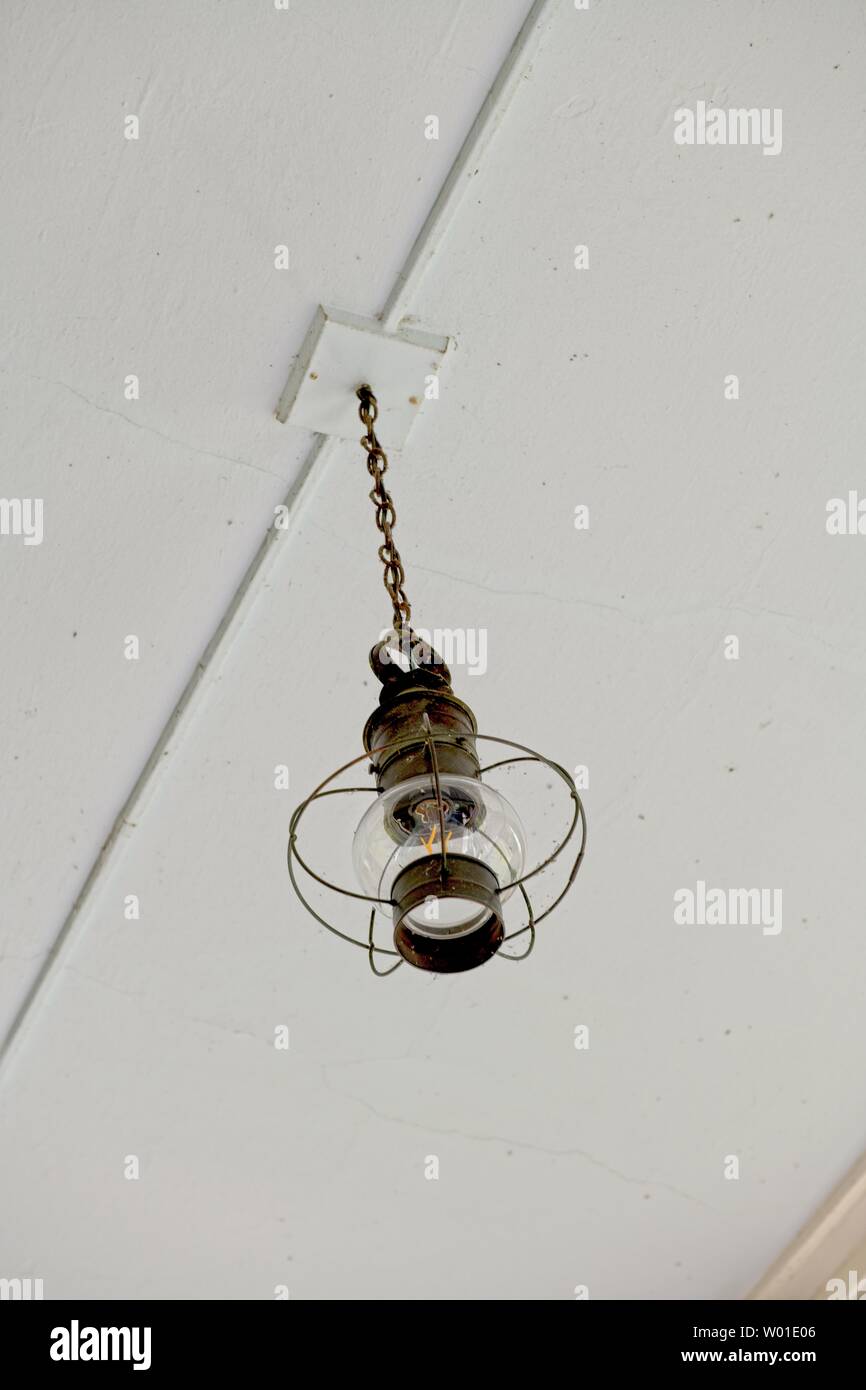 An antique light hanging from a white ceiling Stock Photo