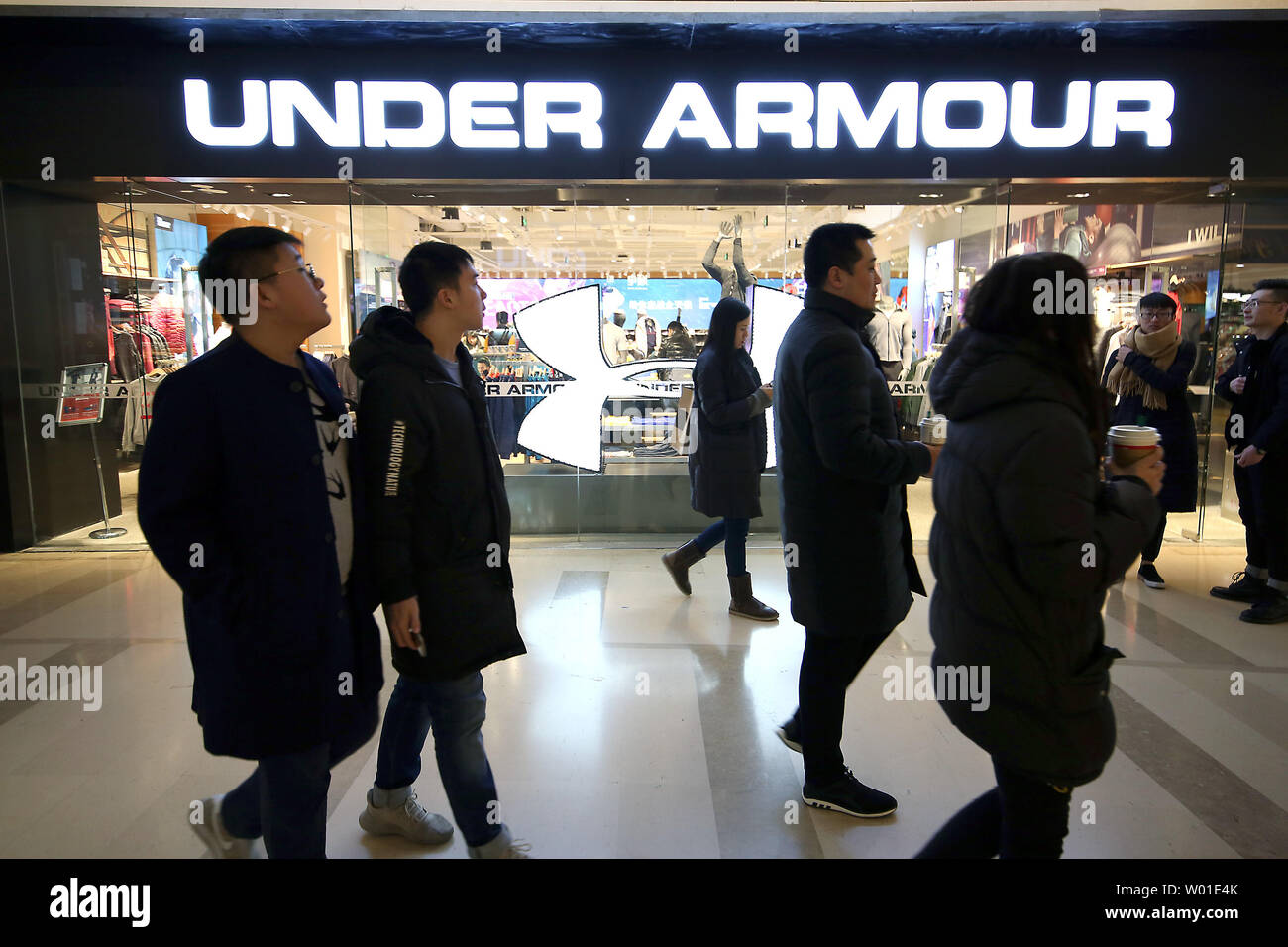 Chinese shoppers walk past a newly-opened Under Armour sporting goods store  in Beijing on February 5, 2018. Due to the premium sports clothing brand's  success in China, several Chinese companies have unveiled